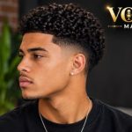 Low Taper Fade Curly Hair with natural textured curls and a clean, low fade around the sideburns and neckline